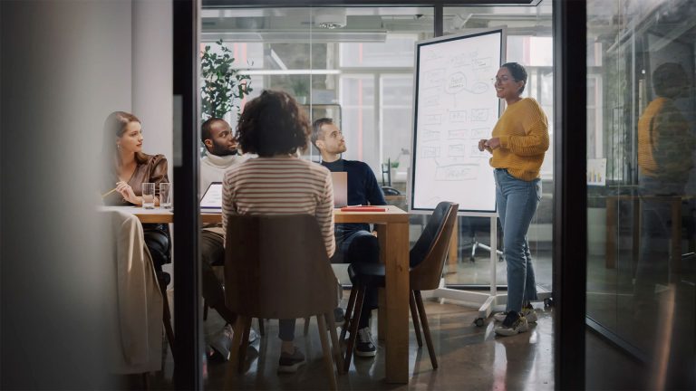 Groupe de collaborateurs autour d’une table, avec des ordinateurs portables et des documents.