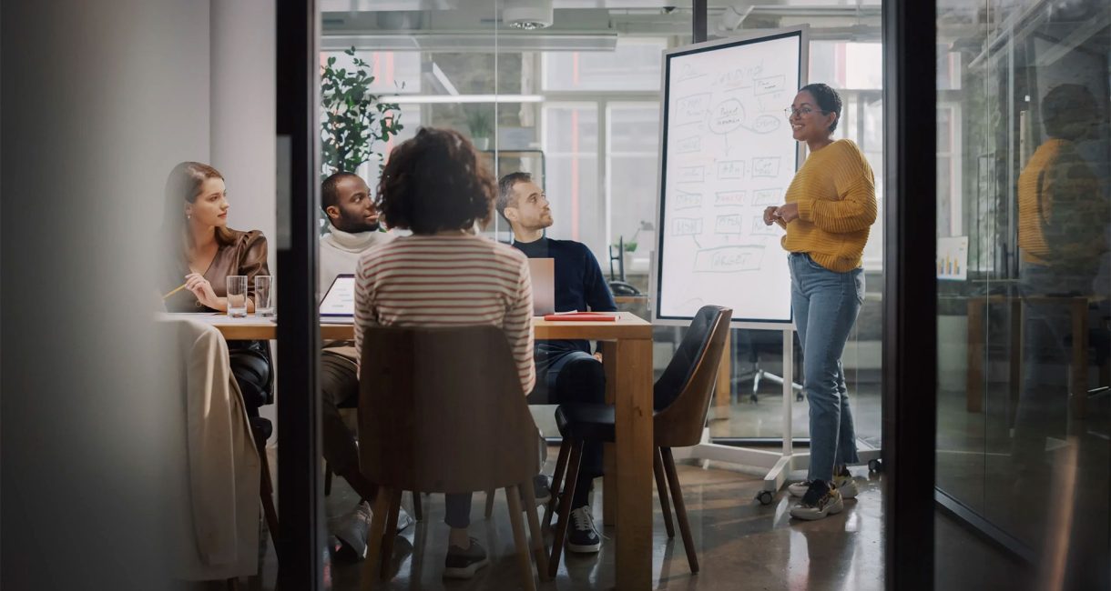 Groupe de collaborateurs autour d’une table, avec des ordinateurs portables et des documents.